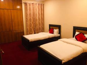 罕萨Green Guest House Altit Hunza的酒店客房 - 带两张带红色枕头的床