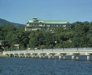 蒲郡市蒲郡古典酒店 的一座水面上的桥梁,一座建筑的背景