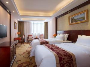 宝安维也纳酒店深圳石岩石龙社区店的酒店客房设有两张床和电视。
