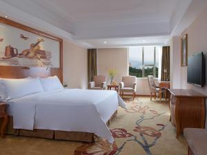 深圳维也纳国际酒店深圳草埔金稻田店的酒店客房设有一张白色大床和一台电视。