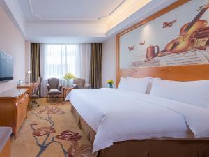 广州维也纳国际酒店广州长隆祈福新邨店的酒店客房设有一张大床和一张书桌。