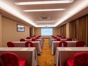 广州维也纳酒店广州番禺南村店的一间会议室,配有桌子和红色椅子以及屏幕