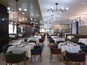海口维也纳酒店 (海口国际会展中心店)的餐厅设有白色的桌椅和吊灯。