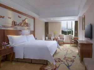 深圳维也纳国际酒店深圳草埔金稻田店的一间带白色大床的卧室和一间客厅