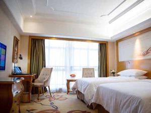 宣州区维也纳国际酒店安徽宣城花园店的酒店客房设有两张床、一张书桌和一个窗户。