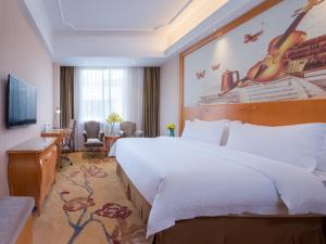 广州维也纳国际酒店广州长隆祈福新邨店的酒店客房设有一张大床和一张书桌。