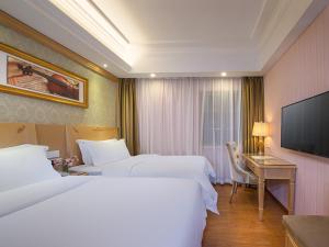 广州维也纳3好酒店广州会展中心赤岗店的酒店客房设有两张床、一张桌子和一台电视。