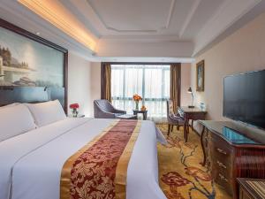 惠东维也纳国际纳酒店惠州惠东红海湾店的一间酒店客房,配有一张大床和一台平面电视
