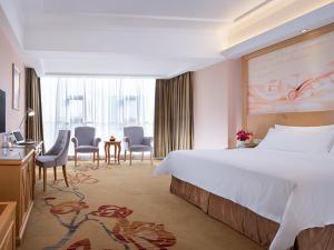 广州维也纳酒店广州番禺华南碧桂园店的酒店客房带一张床、一张桌子和椅子
