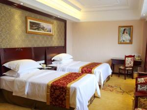 南汇维也纳国际酒店上海浦东新场古镇地铁站店的酒店客房配有两张床和一张书桌