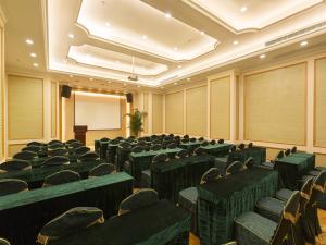 长沙维也纳国际酒店湖南长沙红星店的一间会议室,配有绿色椅子和屏幕