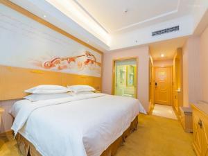 西宁维也纳酒店青海西宁胜利路店的卧室配有一张白色大床,墙上挂有绘画作品