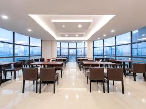宝安维也纳酒店深圳松岗沙江路店的餐厅设有桌椅和大窗户。