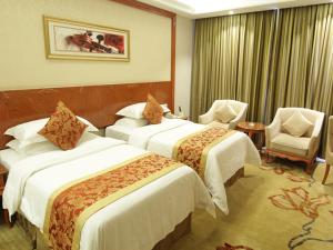 平凉维也纳智好酒店崆峒大道店的酒店客房,配有两张床和两把椅子