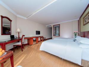 襄阳维也纳酒店襄阳火车站店的卧室配有一张白色大床和一张书桌
