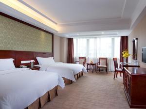 龙岗维也纳酒店深圳龙岗龙东店的酒店客房带两张床和一张桌子以及椅子。