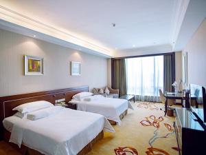 龙岗维也纳国际店深圳华南城店的酒店客房设有两张床和电视。