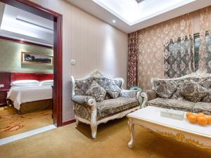 松江维也纳酒店上海松江万达店的客厅配有2张沙发和1张床