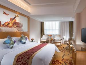 宝安维也纳酒店深圳福永地铁站店的酒店客房设有一张大床,墙上挂有吉他