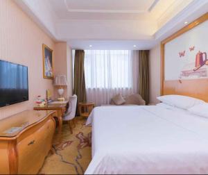 龙岗维也纳酒店深圳宝能城市广场店的酒店客房,配有床和电视