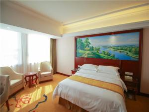 荣成维也纳国际酒店山东威海荣成店的卧室配有一张大床,墙上挂着一幅大画
