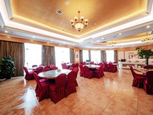 长沙维也纳酒店湖南长沙井湾子木莲中路店的大房间设有红色的桌椅和吊灯