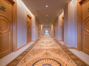 宝安维也纳酒店深圳福永地铁站店的楼面上铺着地毯的酒店走廊