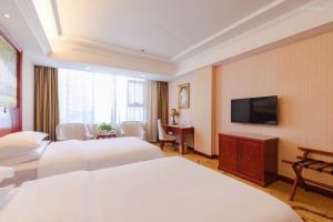 宝安维也纳酒店深圳宝安新安店的酒店客房设有两张床和一台平面电视。
