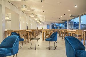 帕拉马Ray Hotel Corfu的配有木桌和椅子以及蓝色椅子的餐厅
