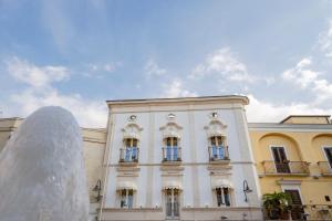 格拉维纳普利亚IL Borgo Relais的一座白色的建筑,前面有一个喷泉
