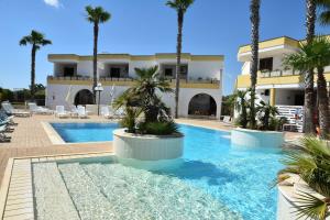 托里德欧索Residence Club Costa D'Oriente的一座楼前棕榈树游泳池