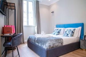 罗马AD Suites Tritone的一间卧室配有一张带蓝色床头板和椅子的床