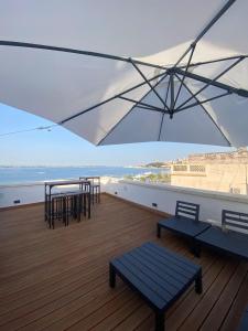 塔兰托A-mare Exclusive Rooms & Suites的阳台配有桌椅和雨伞。