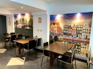 阿姆斯特丹Xplore Hostel Amsterdam的餐厅设有桌椅,墙上挂有绘画作品