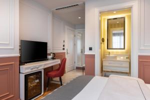 切什梅Motif Hotel Çeşme的一间卧室配有一张床和一张书桌及电视