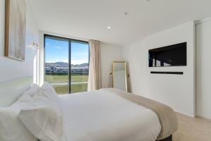 皇后镇La Quinta Queenstown的白色的卧室设有一张大床和一个大窗户