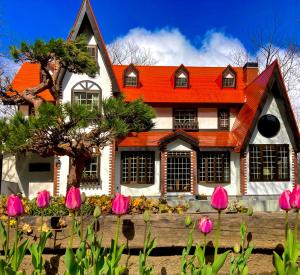 白马村Panketo Lodge & Yoga Studio的一座橙色屋顶和粉红色花卉的房子