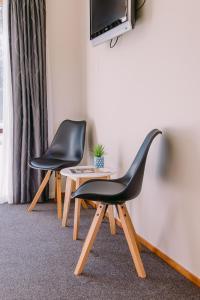 WardFlaxbourne Motels的两张黑色椅子坐在桌子旁,配有电视