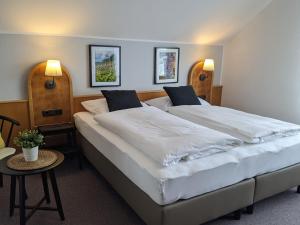 Guntersblum施拉夫多姆霍夫旅馆的一间卧室配有两张床、一张桌子和两盏灯。