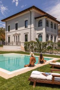 罗马Livia Valeria Palace的两人坐在房子前的游泳池边