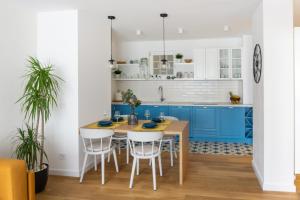 贝尔格莱德Akiton Apartment的厨房配有蓝色橱柜和木桌及椅子