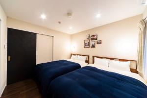 东京GIVE Shibuya Hon-Machi的两张位于酒店客房的床,配有蓝色床单