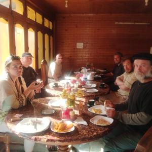 TīshForeigner Tourist Inn的一群人坐在桌子旁吃着食物