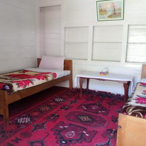 TīshForeigner Tourist Inn的一间设有两张床、一张桌子和一张地毯的房间