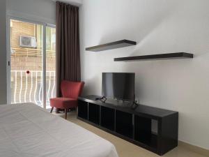 贝尼多姆Hotel Molí Beach的一间卧室配有一张床、一台电视和一把椅子