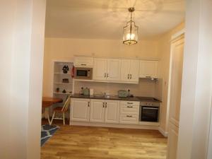 金塞尔Garda House的厨房配有白色橱柜、桌子和吊灯。