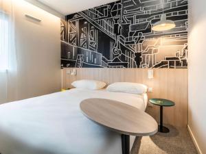 里摩日ibis Styles Limoges Centre的一间卧室配有两张床和一张桌子