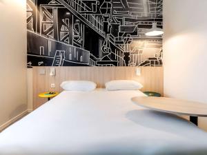 里摩日ibis Styles Limoges Centre的一间会议室,配有一张白色的大床和黑白墙