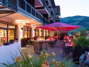 瓦格赖恩Hotel Adapura Wagrain的一间带桌椅和粉红色遮阳伞的餐厅