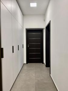 佩奇Jogász Street - A. Apartman的走廊上设有黑色的门和白色橱柜